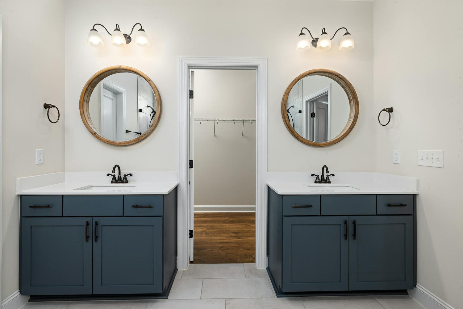 Bathroom with two vanity units, round mirrors, and wall lights.
