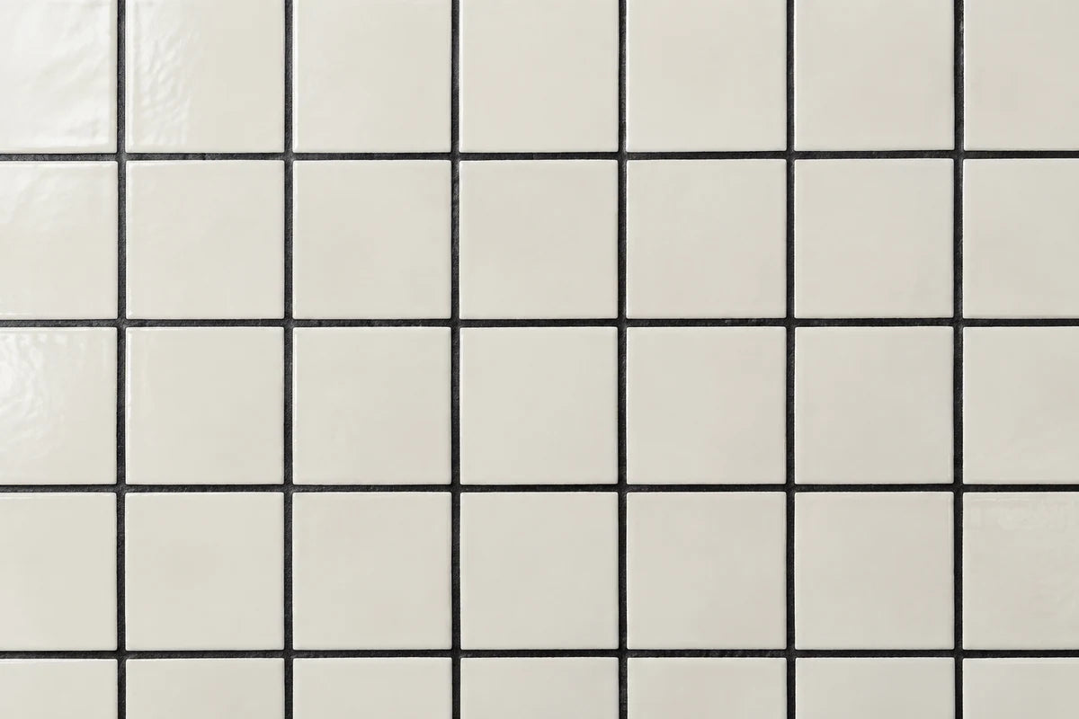 Close-up of crisp ivory small square tile with dramatic black grout grid, realistic clean charcoal-black cement texture and straight consistent joints, color-neutral natural light, no objects