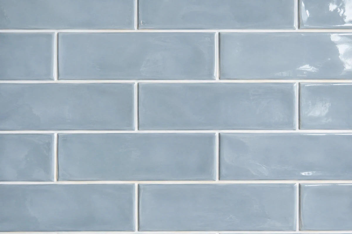 Close-up of soft blue rectangular ceramic subway tiles with bright white grout joints, clear recessed grout texture and subtly glossy glaze, tile fills whole frame, color-accurate daylight