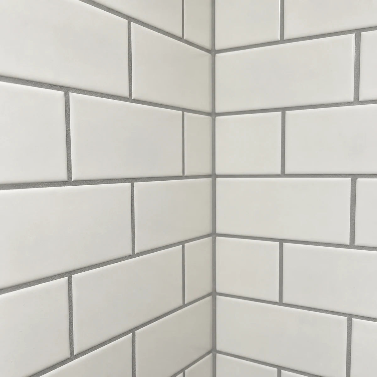 Gray grout defining the joints between warm-white subway tiles