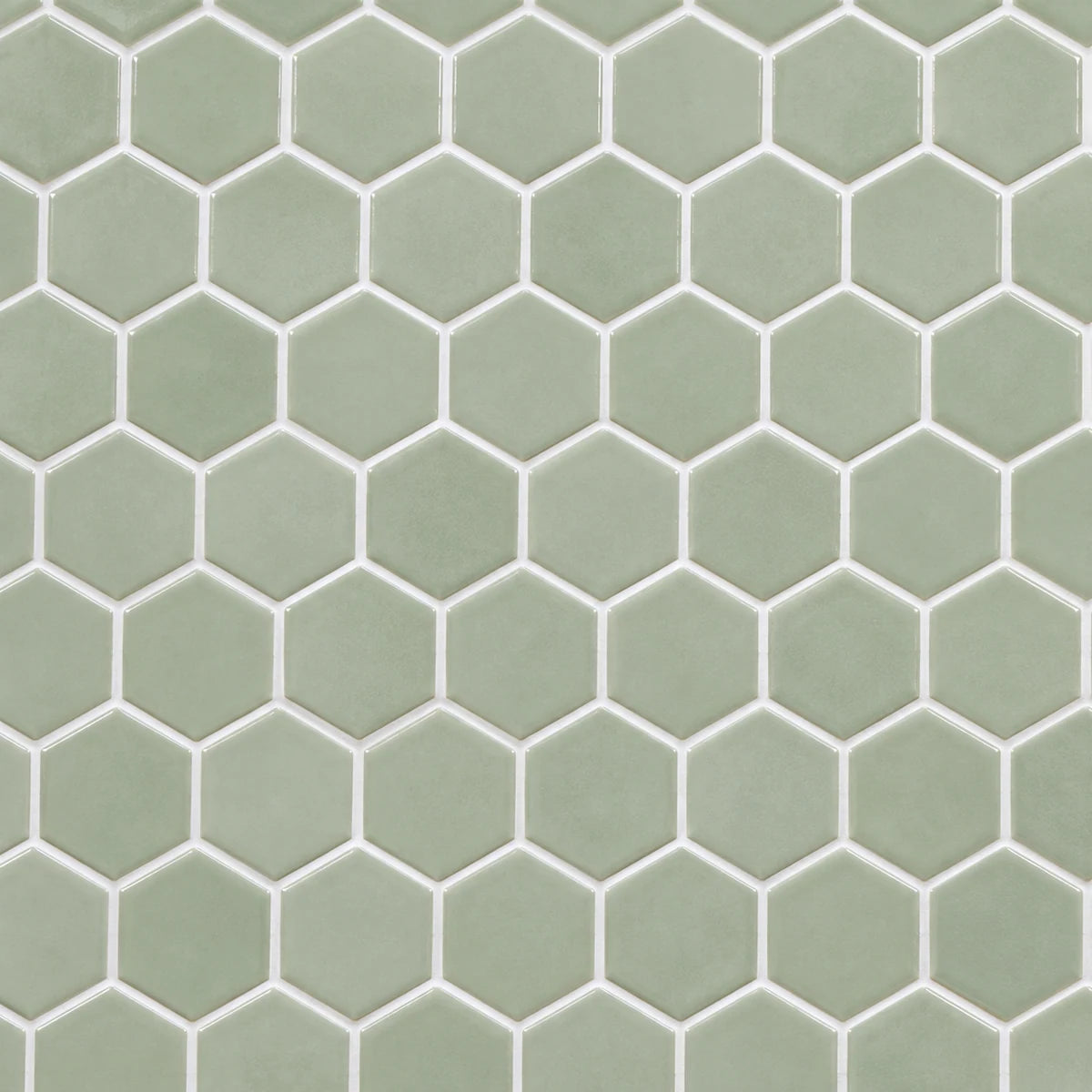 White grout outlining pale sage-green hexagonal ceramic tiles