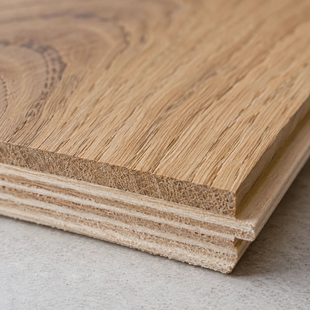 Close-up of an engineered wood plank edge showing its oak top layer and plywood core.
