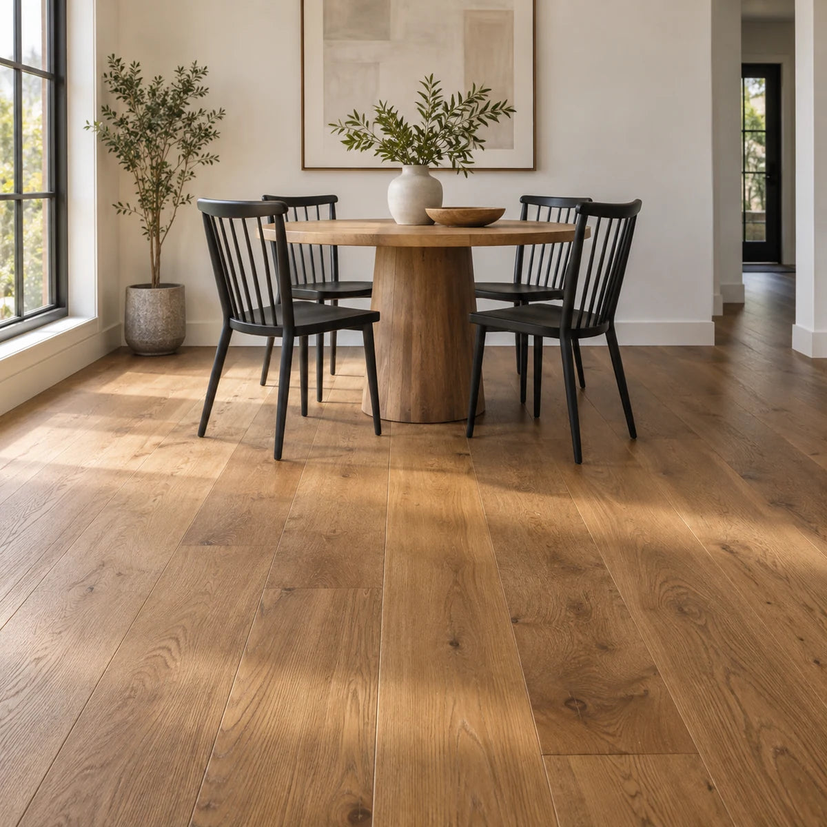Caramel oak flooring beneath a round dining table and black chairs.