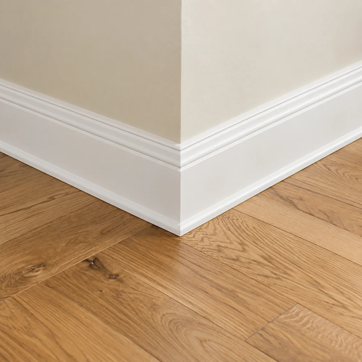 White baseboard molding meeting an oak floor at a wall corner.