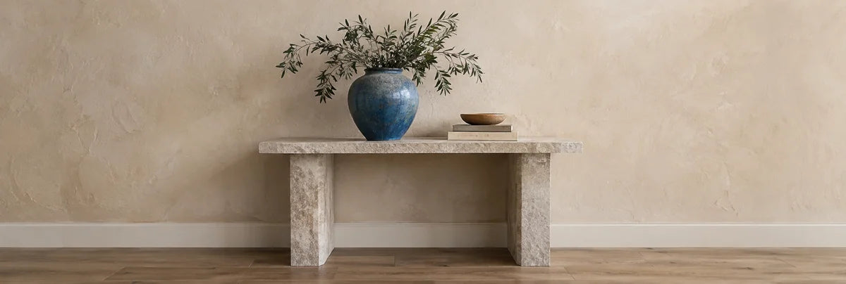 Blue ceramic vase on a stone console against a textured plaster wall